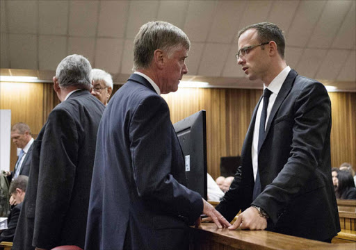 Oscar Pistorius (R) speaks to a member of his legal team during his trial at the high court in Pretoria, April 7, 2014. REUTERS/Themba Hadebe/Pool