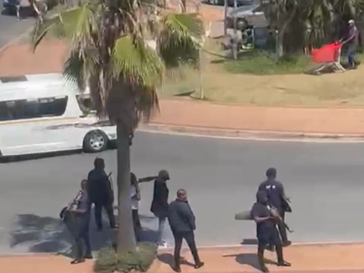Armed men, believed to be bodyguards of minibus taxi operators, stand at the side of the road at the Oceans Mall in Umhlanga, near Durban.