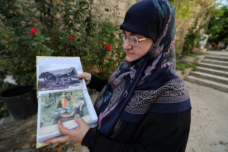 Rabab Youssef, 57, a survivor of the Israeli airstrike in 2006 that killed dozens, shows a photograph of her daughter's body being carried by a rescuer as she speaks to journalists outside the house in Qana, Lebanon on October 24 2023. Picture: REUTERS/Zohra Bensemra