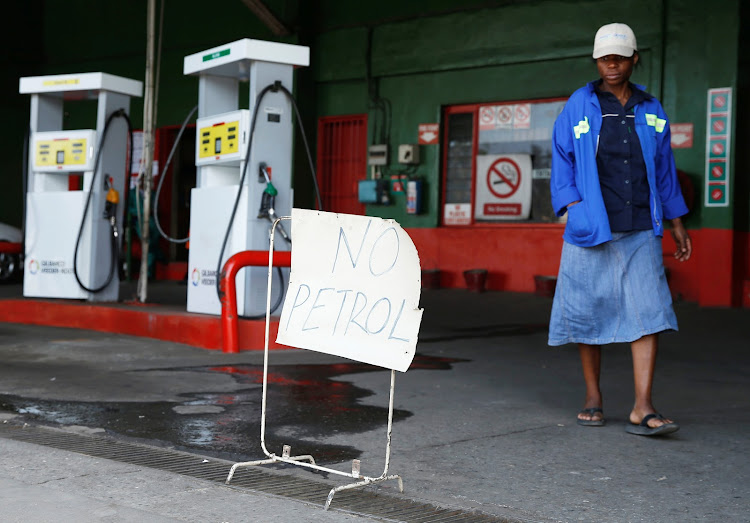 A woman walks past a "No Petrol" sign at a fuel station in Harare, Zimbabwe, October 9, 2018.