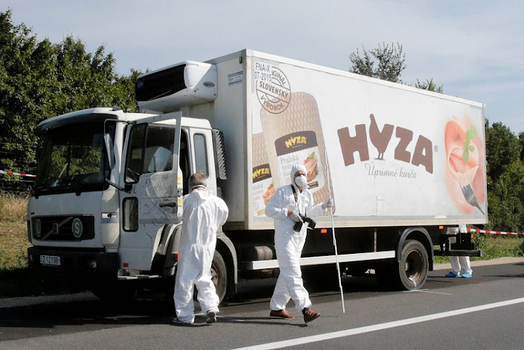 Forensic police officers inspect a parked truck in which 71 migrants were found dead, on a motorway near Parndorf, Austria on August 27, 2015. Four human traffickers were jailed for life in a final ruling in a Hungarian court on June 20, 2019 for the deaths of the migrants four years ago.