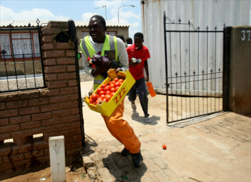 Residents carry goods which they took from a looted shop owned by foreign nationals on January 22, 2015 in Soweto. File photo.