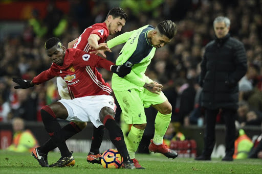Manchester United's French midfielder Paul Pogba (L) vies with Liverpool's Brazilian midfielder Roberto Firmino (C) as Manchester United's Portuguese manager Jose Mourinho (R) looks on during the English Premier League football match between Manchester United and Liverpool at Old Trafford in Manchester, north west England, on January 15, 2017.