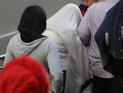 The mother of the baby that was rescued from a storm-water drain in Newlands  leaves the Ntuzuma court under a veil and flanked by family on Monday.