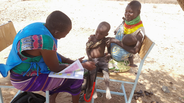 Magret Ikimat Community Health Volunteer of Nameyana village, Turkwel Ward, Loima Sub County in Turkana observing the chest of Jackson Esinyen two years old and counting the beads by breath to diagnose pneumonia