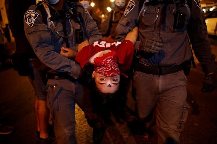 Policemen carry a woman during a protest against Israeli Prime Minister Benjamin Netanyahu's alleged corruption and economic hardship stemming from lockdown during the coronavirus disease (COVID-19) crisis, near his residence in Jerusalem September 13 2020.