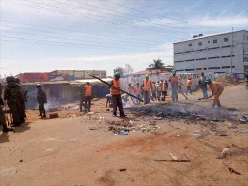 Construction workers help police to clear roads blocked in Bungoma during protests over the repeat presidential election, October 27, 2017. /JOHN NALIANYA\