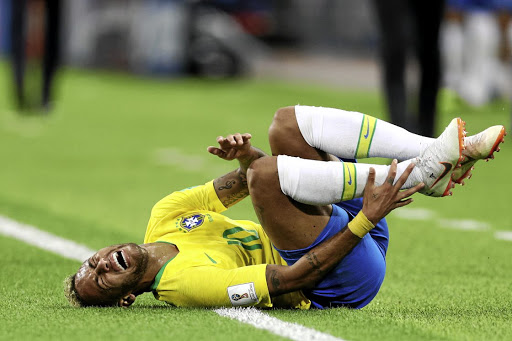 Neymar screams in pain after being fouled. The writer says his antics are so popular kids are now encouraged to roll on the ground during play to feign injury.