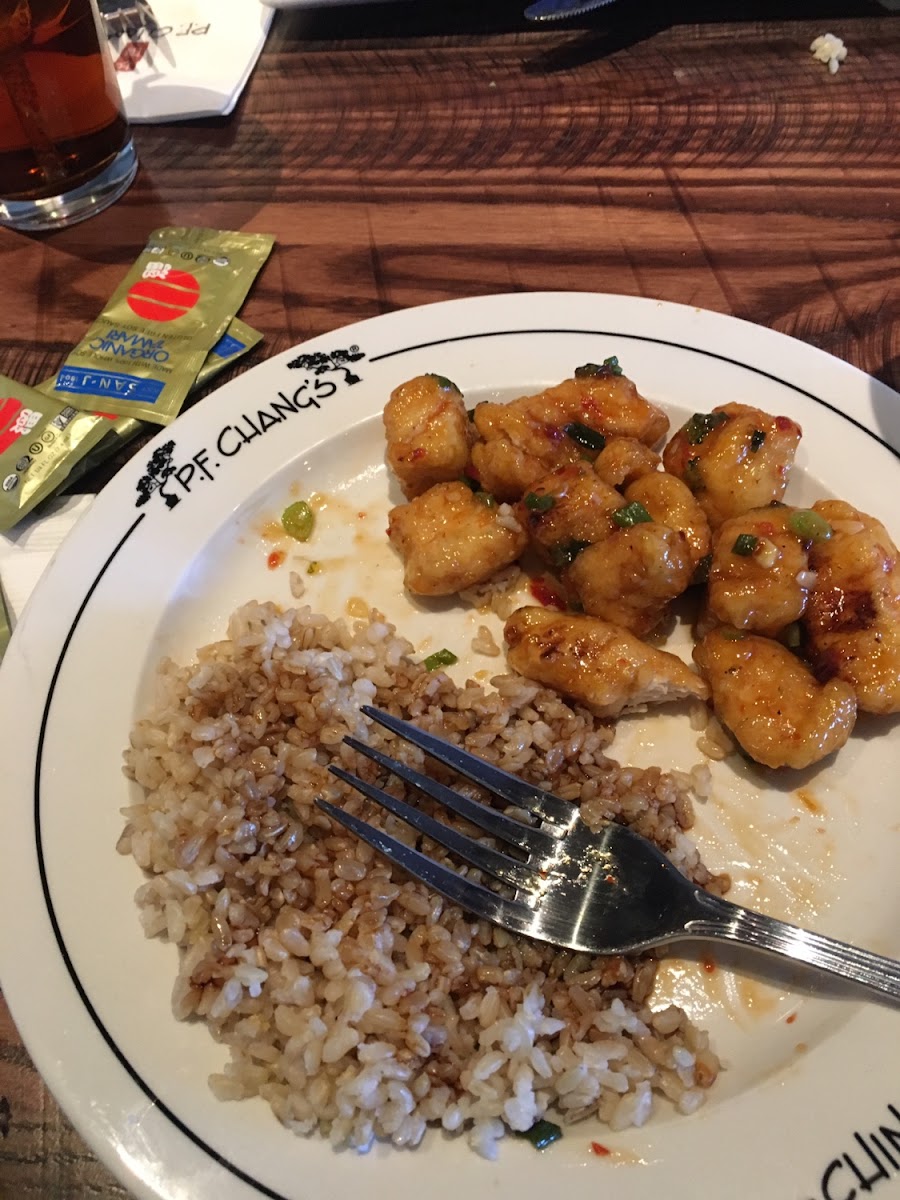 Chang's Spicy Chicken with a side of brown rice and gluten free soy sauce. Served on a marked plate to indicate gluten free.