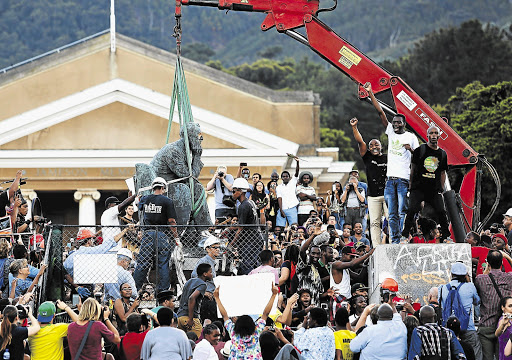 FALL GUYS: A month to the day since Chumani Maxwele (left, on the plinth) started the Rhodes Must Fall protest, he and fellow students celebrate as the statue of Cecil John Rhodes is taken from the heart of the UCT campus yesterday