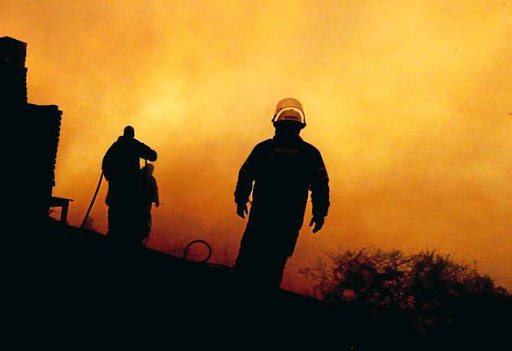Fire-fighters battle to save a house in Buffalo Bay near Knysna yesterday as the fires along the Garden Route flared up again, fanned by gale-force winds.
