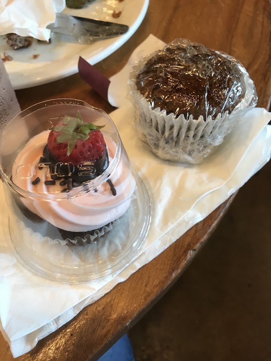 Chocolate cupcake with strawberry buttercream icing and a chocolate covered strawberry on top and a pumpkin muffin