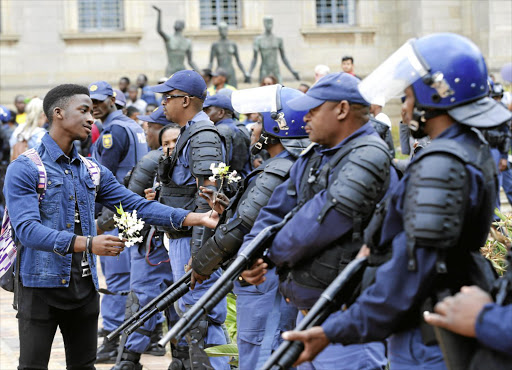 A student offers a flower to a police officer after clashes over tuition fees at the University of the Witwatersrand last year. File photo.