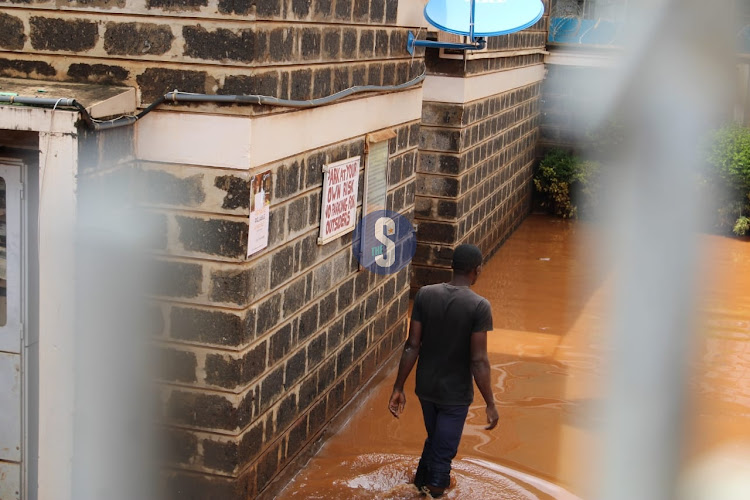 A man walking inside the flooded Supa Care apartments, Ruaka on April 24, 2024.