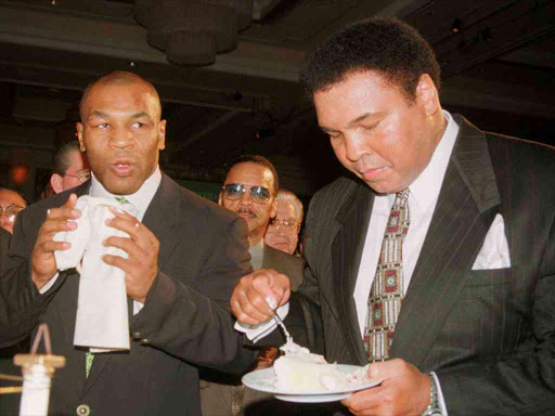 Boxing great Muhammad Ali (R) eats a piece of his birthday cake as boxer Mike Tyson looks on at the MGM Grand hotel in Las Vegas, Nevada in this January 17, 1999 file photo. Photo/REUTERS