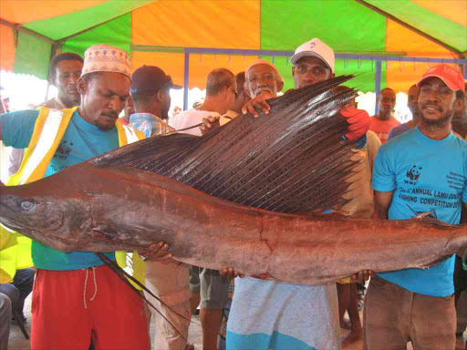 Captain Yusuf Harun (centre) shows his 32 kilogramme sailfish which he caught during the third Lamu annual fishing competition, December 12, 2016. /ALPHONCE GARI