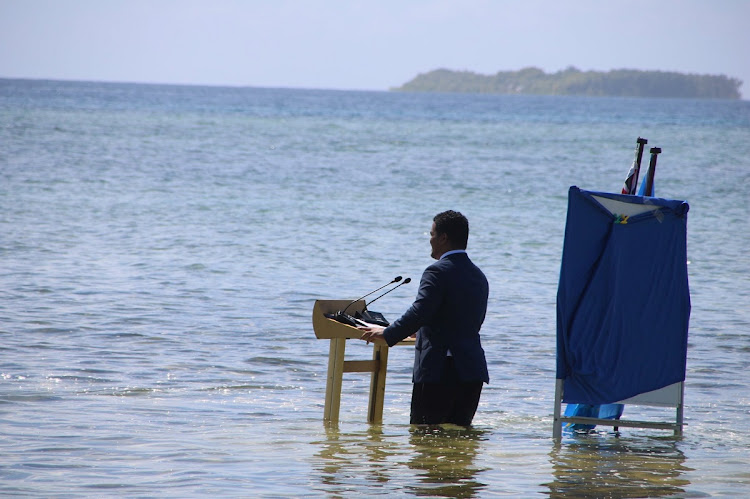 Tuvalu minister Simon Kofe gives a COP26 statement while standing in the ocean in Funafuti.