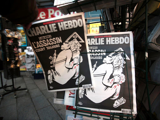 A man takes a copy of the latest edition of French weekly newspaper Charlie Hebdo with the title "One year on, The assassin still on the run" displayed at a kiosk in Nice, France, January 6, 2016. Photo/REUTERS