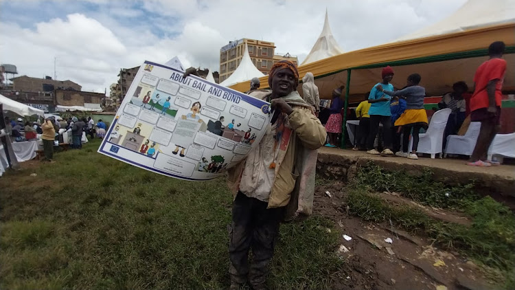 A member of the public display a sensitization poster during the Mavoko Law Courts Open Day in Mlolongo, Machakos County on April 26, 2024.