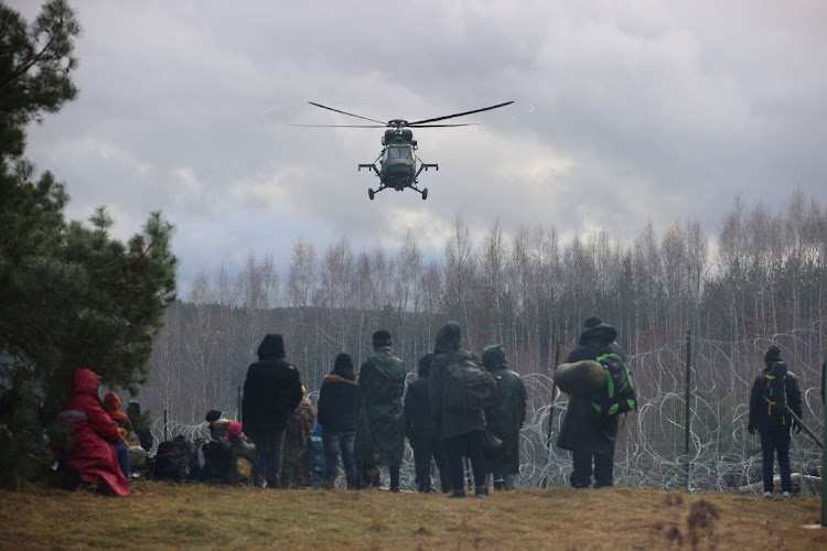 A helicopter hovers above migrants on the Poland-Belarus border. Picture: REUTERS/LEONID SCHEGLOV/BELTA