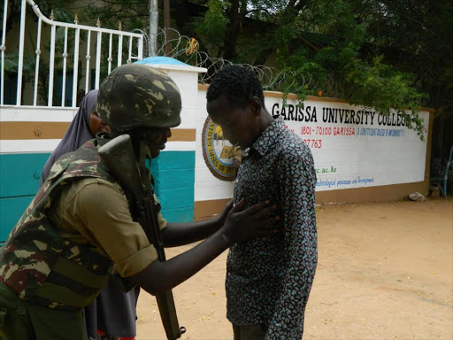 A non-teaching staffer at the Garissa University College is frisked by a security officer yesterday.