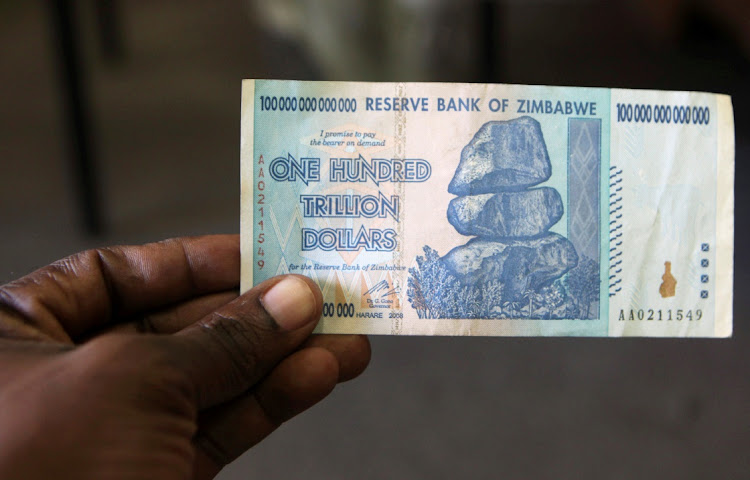 A man holds up for a picture a one hundred trillion Zimbabwean dollars note inside a shop in Harare, Zimbawe in June 2015. Picture: REUTERS/ PHILIMON BULAWAYO