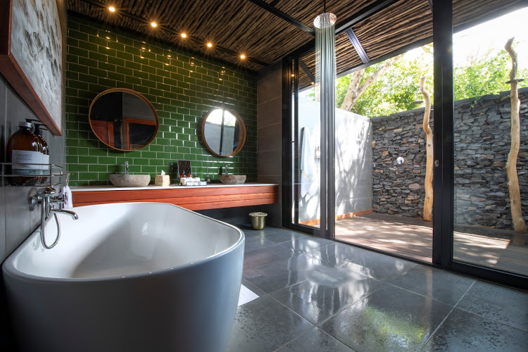 The bathroom with its twin vanities and soaking tub opens onto a double outdoor shower.