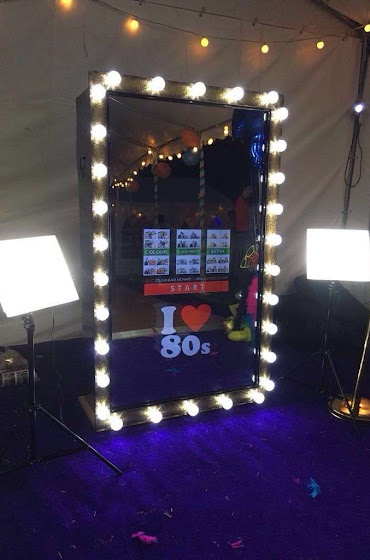 A mirror booth with an I love the eighties icon