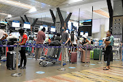 Masked commuters queue at OR Tambo International Airport. Local airlines are taking different approaches to the lockdown limitations on air travel.