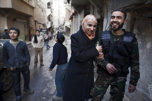 Yusef (R) and Ghada pose in a street after getting married in the Sukkari district of Aleppo, in northern Syria, on January 17, 2013.