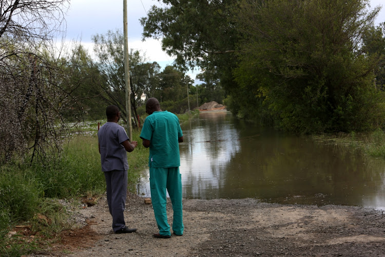 Two doctors assess a submerged road in Bloemhof, after being evacuated due to floodwaters.