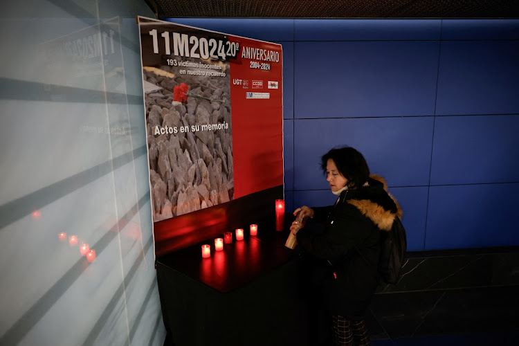 A woman lights a candle at Atocha train station on the day of a memorial for the March 11 2004 train bombings, on its 20th anniversary in Madrid, Spain, on Monday. Picture: REUTERS/JUAN MEDINA