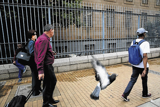 PIGEON ENGLISH: Hate-speech accused Elvira Oelofse leaves the Johannesburg Equality Court with her husband as a bird of the type she tried to protect flies by unconcerned