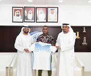 Former Cape Town City forward Ayanda Patosi flanked by officials from his Saudi Arabian team. 