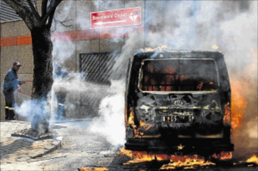 UP IN SMOKE: A Post Office van burns at the Saxonwold depot, Rosebank, after it was set alight by striking workers