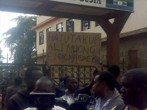 A Busia County resident holds up a protest sign following the disbandment of the Budget and Appropriations Committee, June 20, 2018. /JANE CHEROTICH
