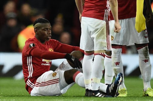 Manchester United's French midfielder Paul Pogba (L) sits on the pitch injured during the UEFA Europa League round of 16 second-leg football match between Manchester United and FC Rostov at Old Trafford stadium in Manchester, north-west England, on March 16, 2017.