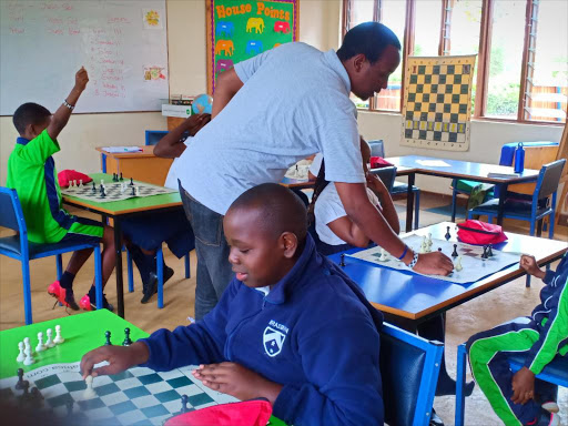 MiniChess Kenya coach Githinji Hinga shares tips with junior players at Braeburn Imani chess club, Nairobi