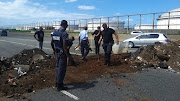 Municipal workers clean up debris and sand left by striking municipal workers on a freeway near Isipingo, south of Durban