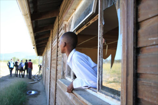A pupil at Vukile Tshwete High School, in Keiskammahoek, outiside King Williams Town sticking out of a broken window during a visit by Equal Education. - Sisipho Zamxaka