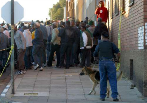 Spectators outside a Jeppe house where robbers took refuge after stealing from a Pick 'n Pay supermarket in Honey Dew. Pic: Antony Kaminju. Circa September 2006. © Sunday Times. BLOODBATH: The Jeppe house where alleged robbers hid. Twelve people died including four policemen and eight alleged robbers. page 4, sow 05/02/08.