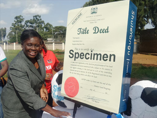 Deputy Chairperson National Lands Commission Abigael Mukolwe explains the contents of a dummy title deed during the launch of the National Guidelines for title deeds applications for schools. Photo/File