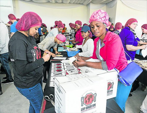 HELPING HANDS: Daily Dispatch volunteers pack nutritious meals in last year's Stop Hunger Now campaign at Hemingways Mall. This year's event takes place at the mall on Saturday. Businesses and individuals have until noon today to sign up to do their bit for Mandela Day Picture: ALAN EASON