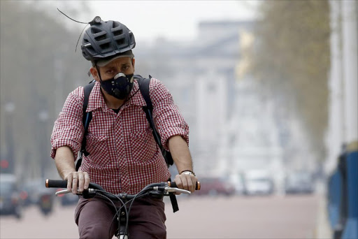 A cyclist wears a mask as he cycles near Buckingham Palace in London. REUTERS/Luke MacGregor