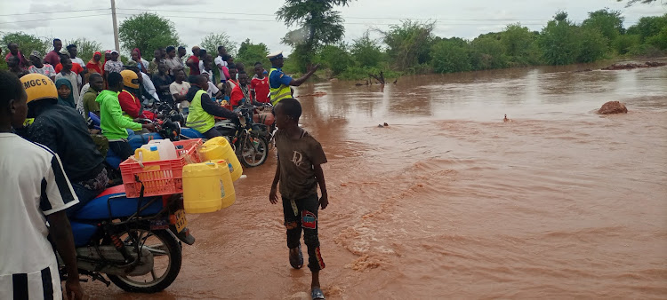 A traffic police officer stops bodaboda riders from crossing from Madogo to Garissa at the Kona Punda section that was destroyed by flash floods