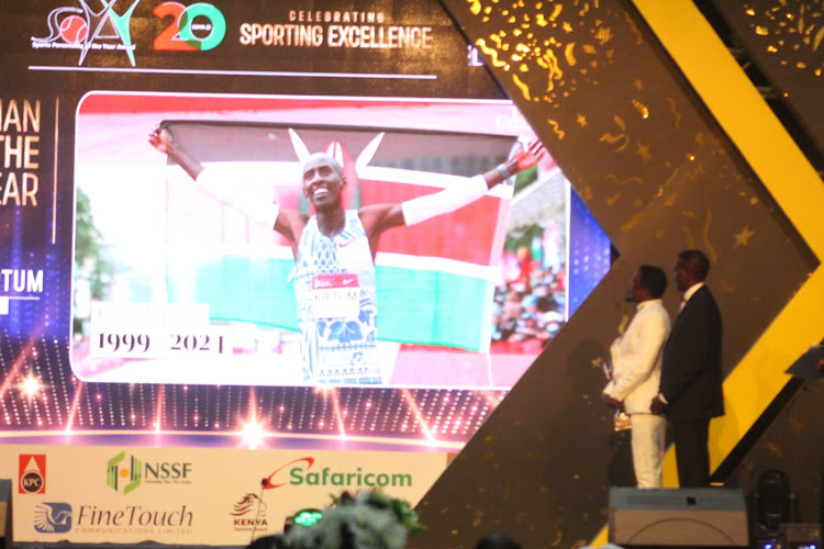 Sports CS Ababu Namwamba and (Noc-K) National Olympic President President Paul Tergat look on at a clip displayed of the late marathon champion Kelvin Kiptum breaking the world record during SOYA awards at the KICC on March 1, 2024