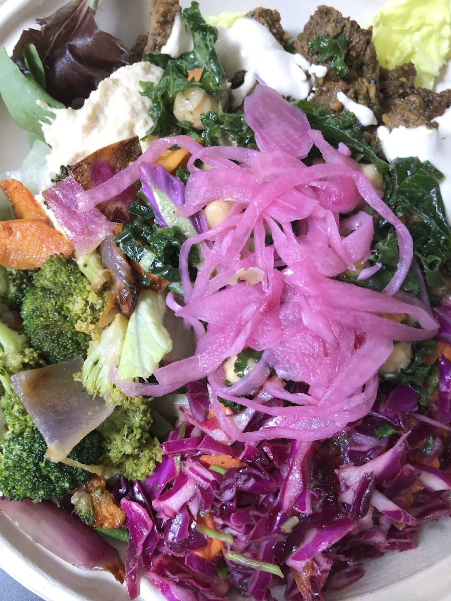 Salad with grass-fed beef, tahini, red cabbage slaw, roasted veggies, pickled onions and hummus.