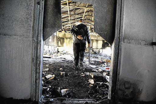 NOT SO CLEVER: A security guard at Auriol College, in Oudtshoorn, Western Cape, in one of the mobile classrooms set alight by gangsters. Gangs have taken over the school and loot it for cable, copper wire and 'anything they can sell for drugs'