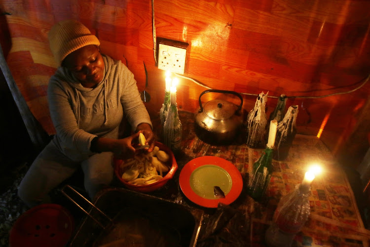 Sinethemba Khunou, who works at Vukusebenze takeaways, uses a gas stove for frying chips and candles to provide the light during load sheding in Nompumelelo.