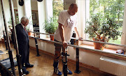 Darek Fidyka (R) walks with the aid of leg-braces and parallel bars. Picture Credit: AFP